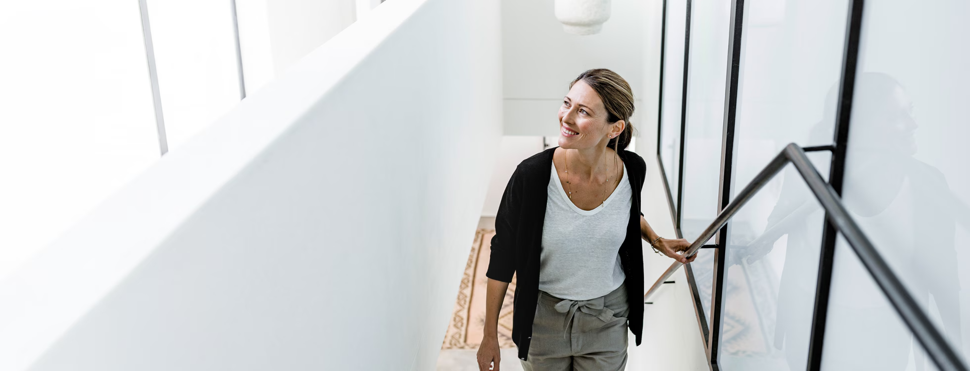 A woman ascending a staircase in a bright, modern home