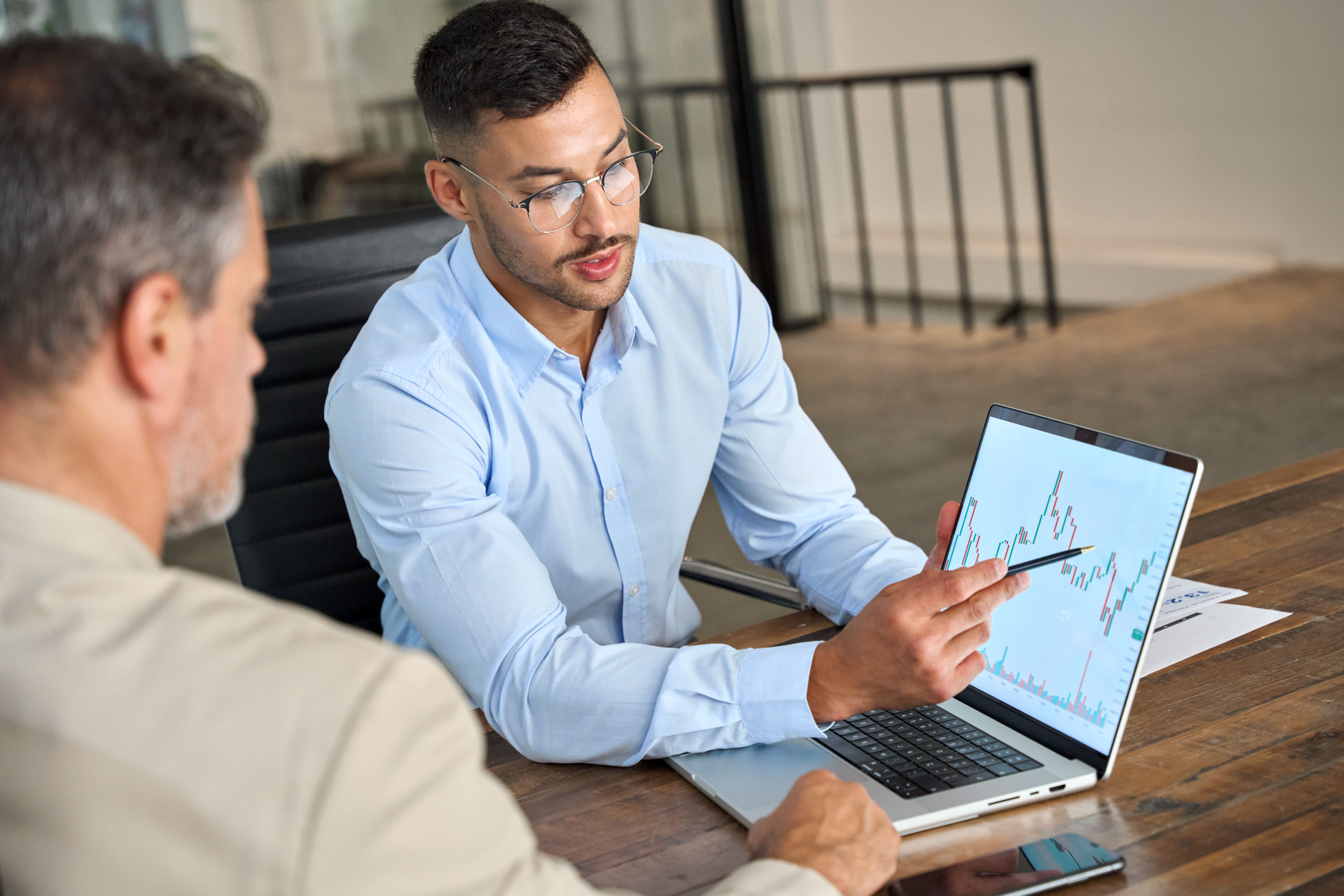 An advisor presenting market charts on a laptop to a client